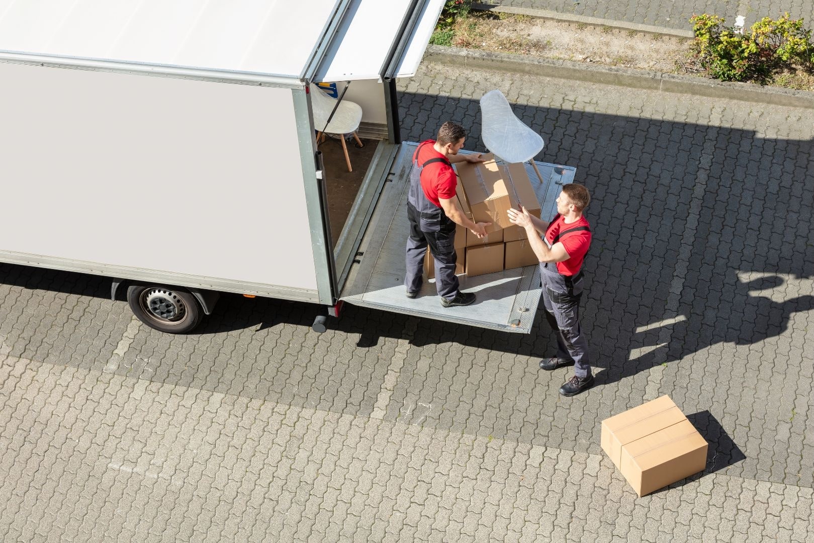 bijrijder laadt dozen bij vrachtwagen